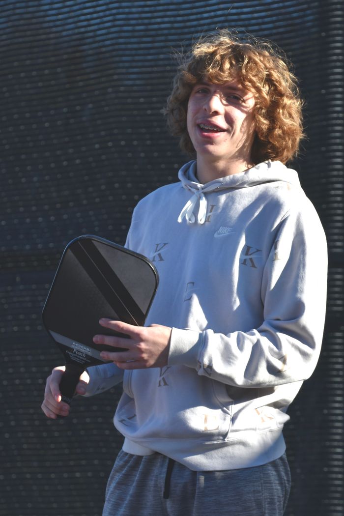 about-us-02 Smiling young man holding paddle on a sunny day ready to play pickleball.