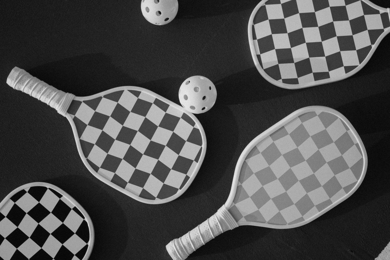 services-02 Top view of checkered paddles and balls on a dark surface, perfect for sports themes.